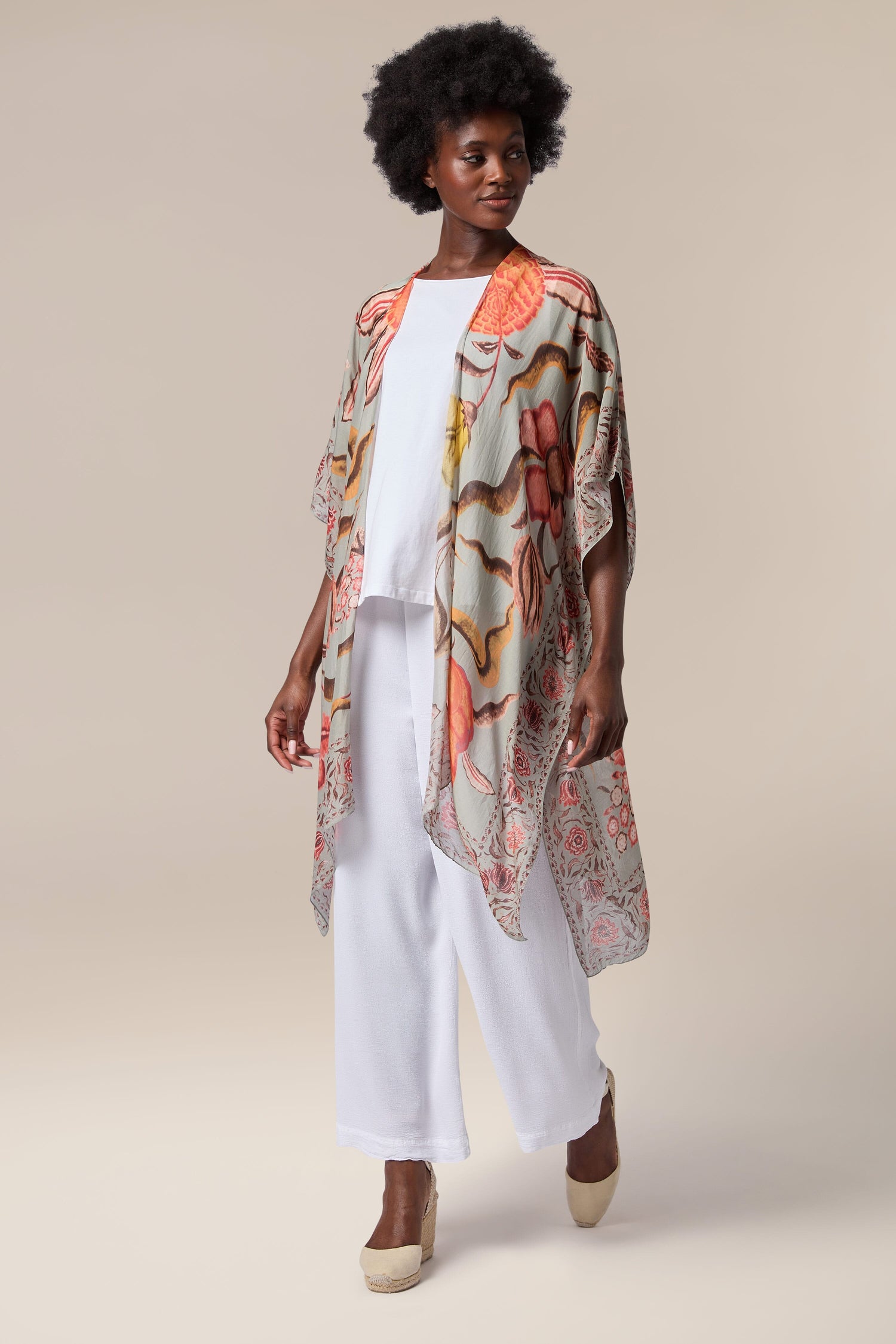 A woman wearing a printed kimono, a Joy Throwover from India, and white pants.