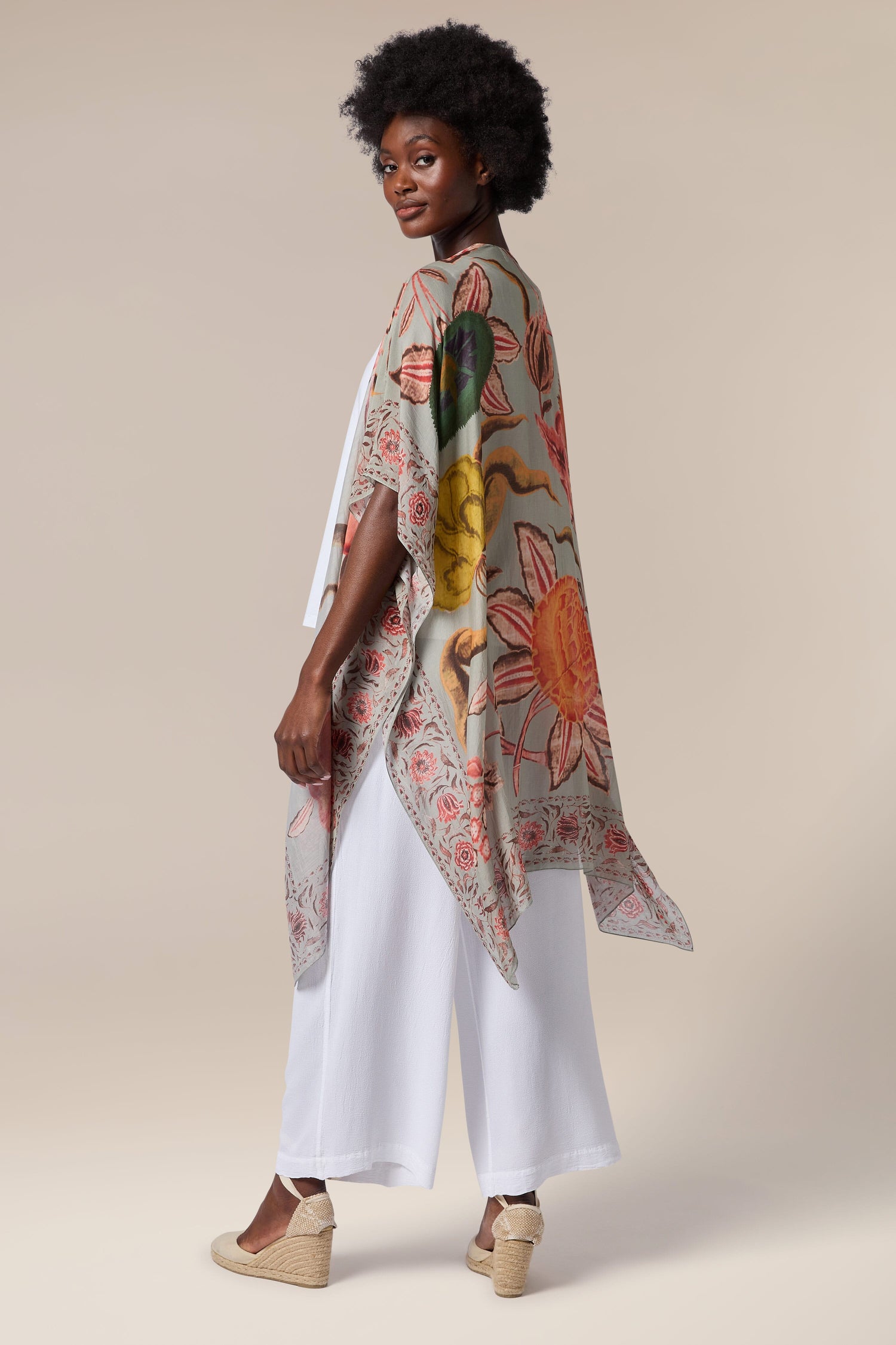 The back view of a woman wearing a floral printed kimono, a Joy Throwover.