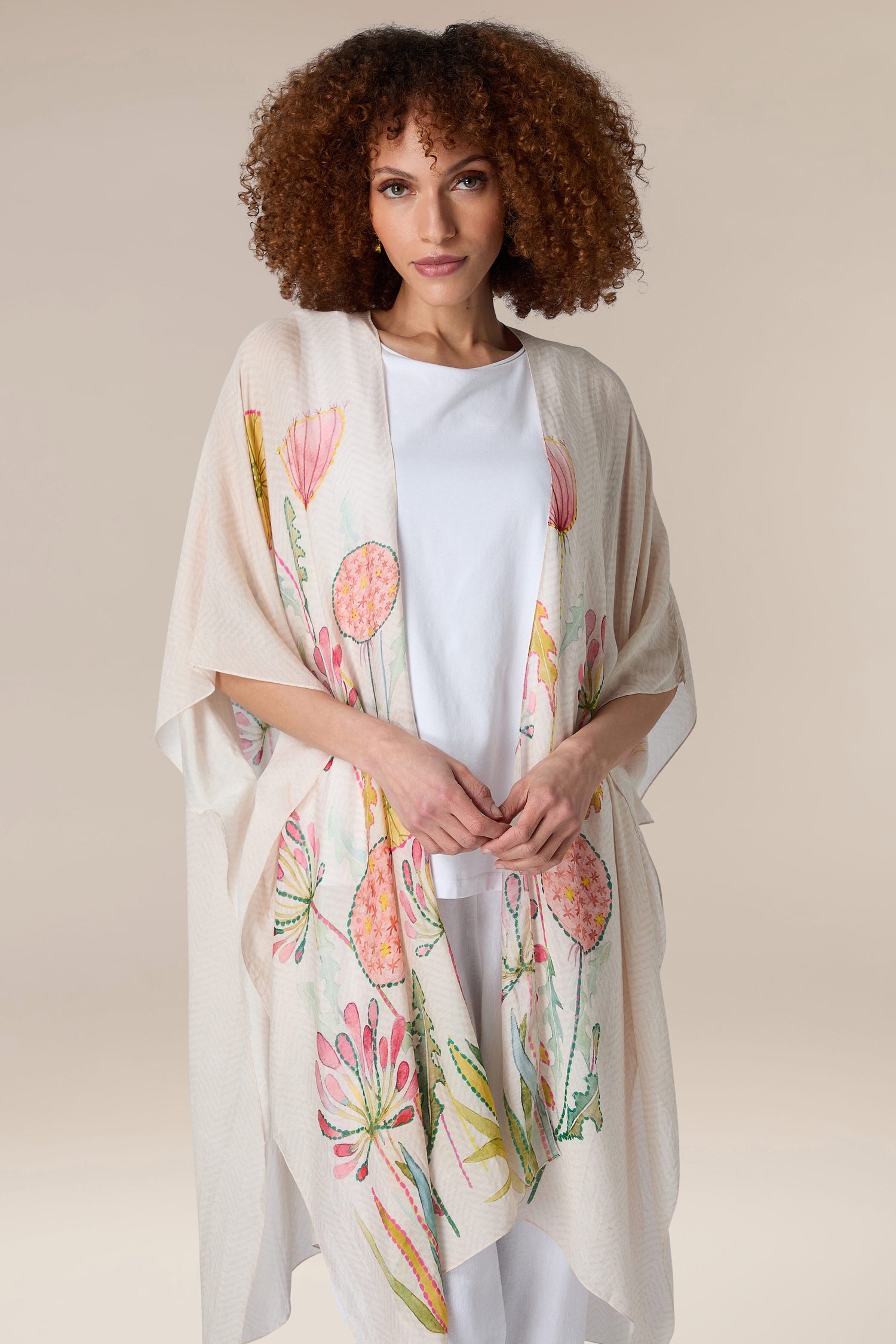 A woman donning a cream kimono with a Pop Flowers Throwover print, suitable for resort wear.