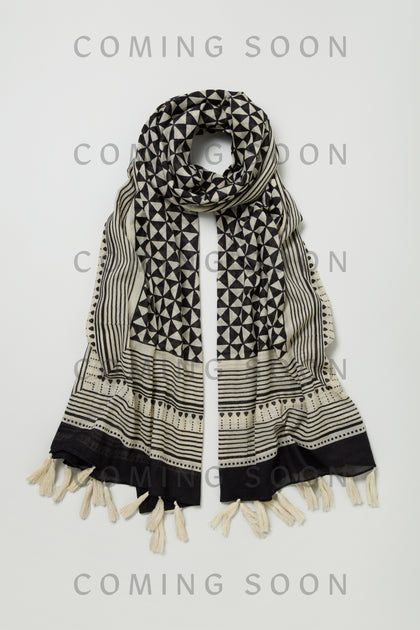 The Cotton Tassel Scarf, style PMC180072A, features black and white geometric patterns and tasseled edges. It's displayed on a light background with "COMING SOON" overlaid on the image.