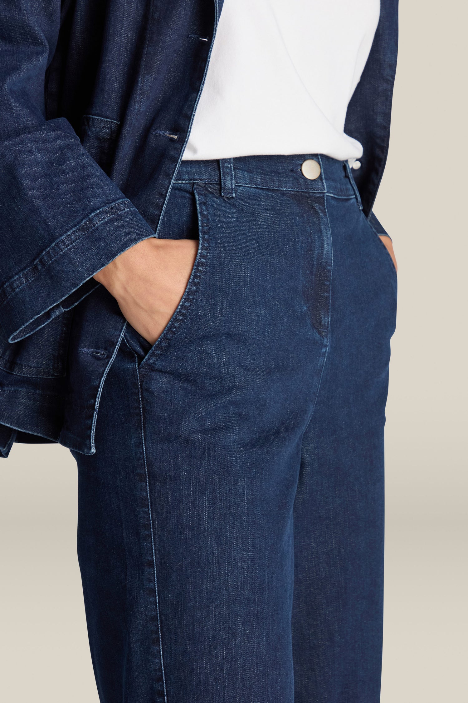 Close-up of a person wearing blue Stretch Denim Barrel Leg Trousers with an elasticated waistband, paired with a white shirt and a blue denim jacket.