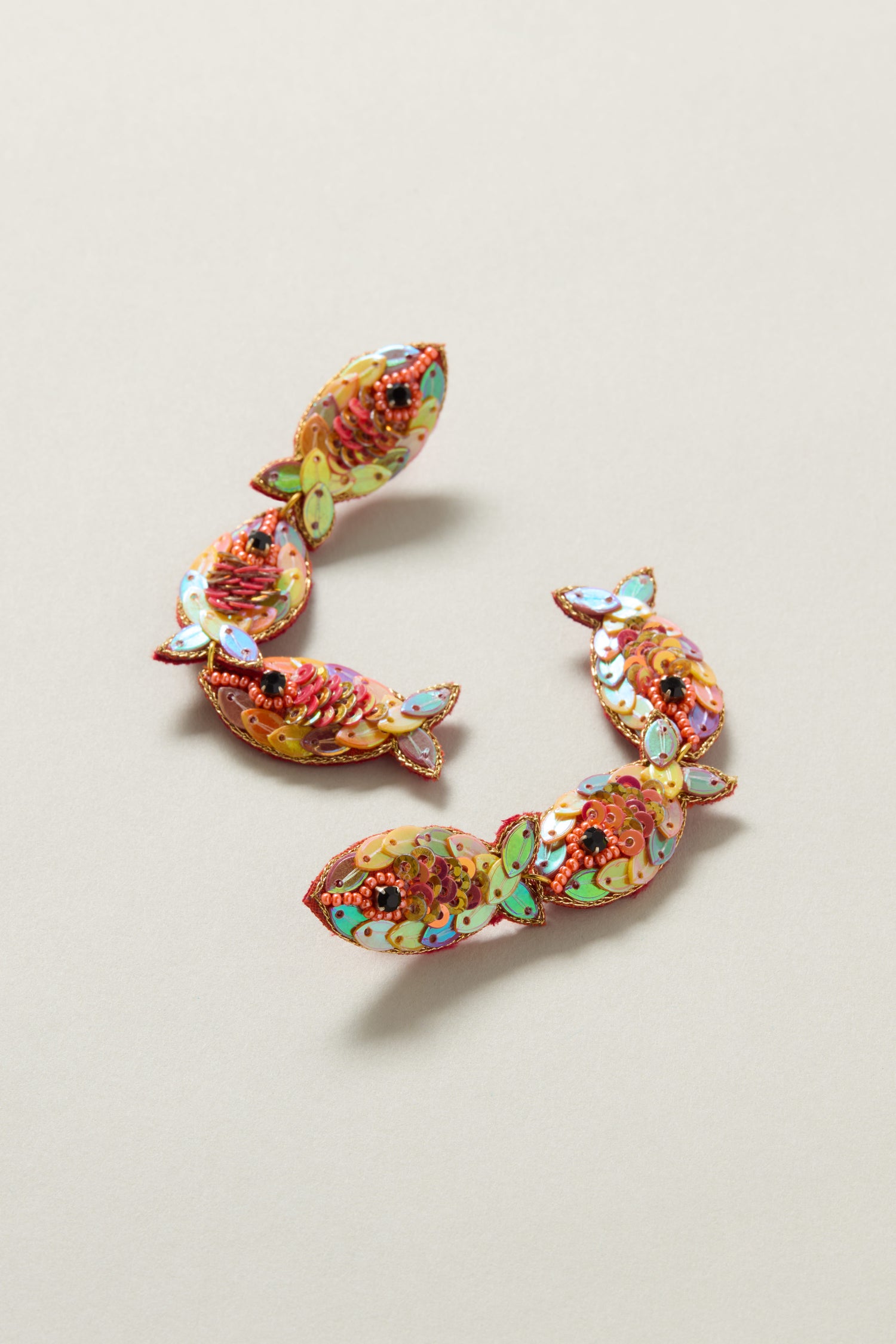 Two vibrant Hand Beaded Poisson Earrings adorned with multicolored details, iridescent beads, and sequins, capturing the whimsical beauty of the ocean against a light backdrop.