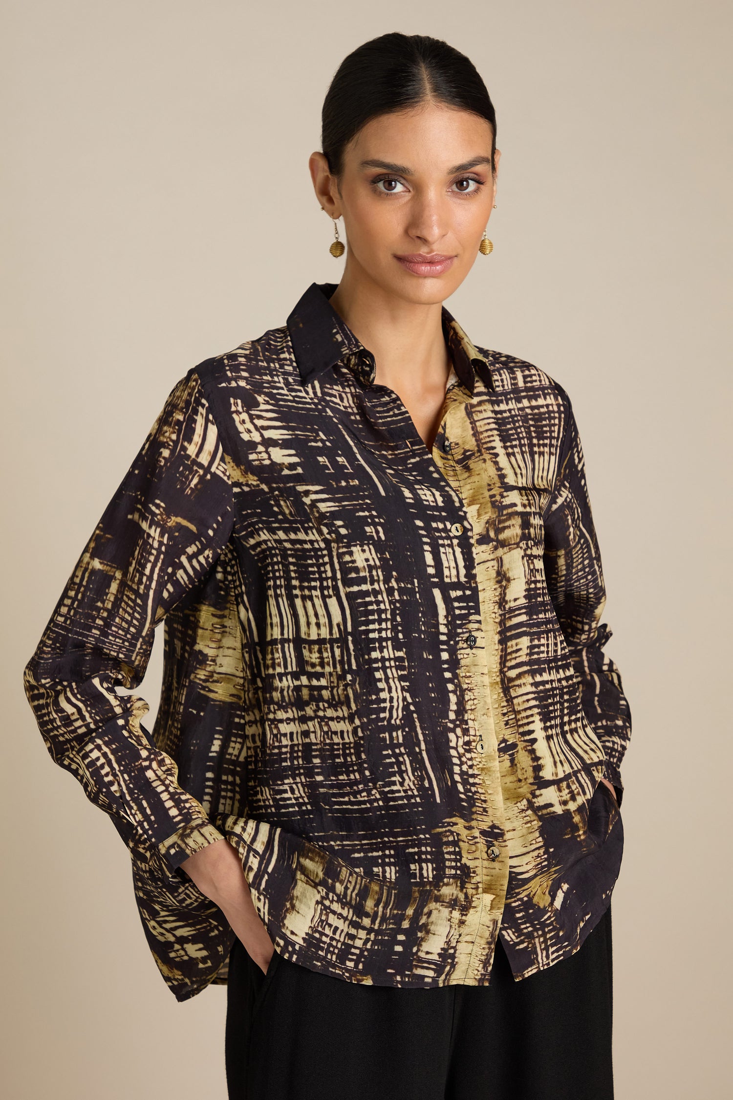 A woman with dark hair is wearing a Cross Hatch Shirt made of silky Viscose and black pants, posing with her hands in her pockets against a neutral background. The relaxed fit of the outfit makes it perfect for a chic daytime look.