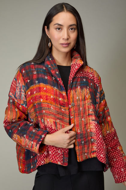 A woman with long dark hair wears the Padded Multi Check Padded Jacket in red, orange, and blue over a black top, standing against a plain background.