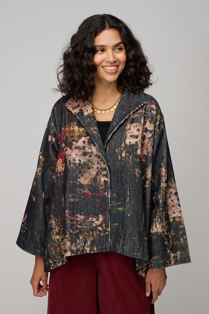 Woman wearing a Print Corduroy Jacket with a relaxed fit over a black top and dark red pants, standing against a plain background.