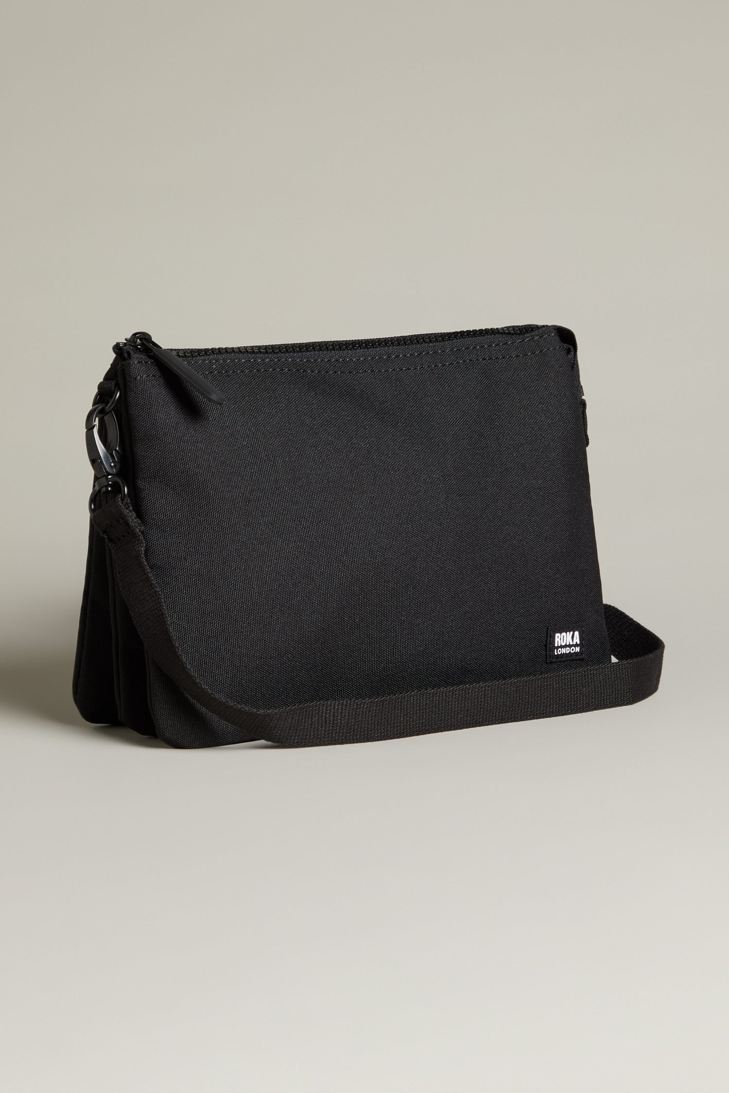 Introducing the Recycled Carnaby Crossbody Bag, a sleek black crossbody crafted from eco-friendly materials. It boasts a minimalist design with a main zipper compartment, an adjustable strap, and weather-resistant properties for all your adventures.