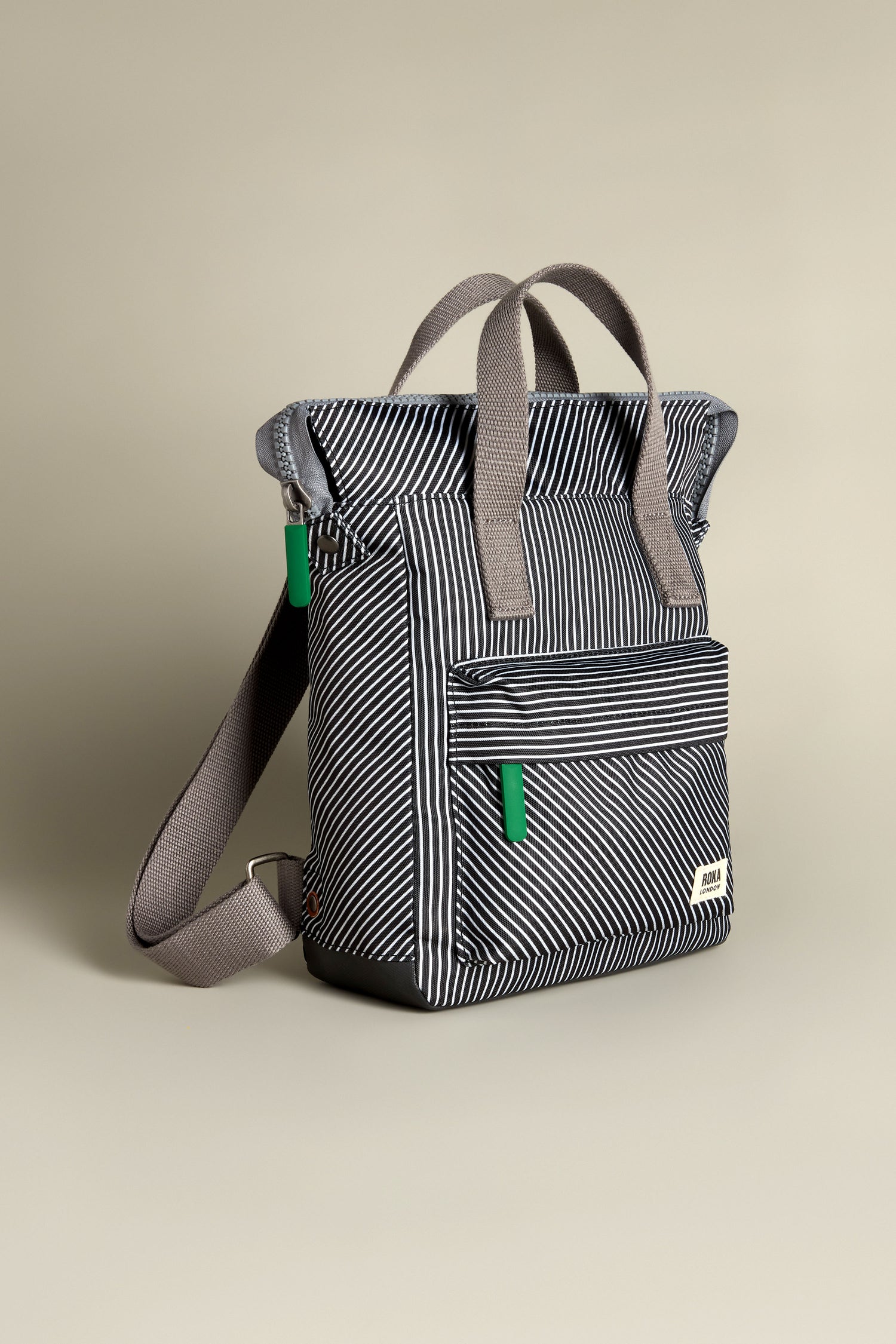 The Recycled Canvas Stripe Bantry Bag is a versatile bag made from recycled canvas with black and white stripes, gray handles, and green accents set against a neutral background.