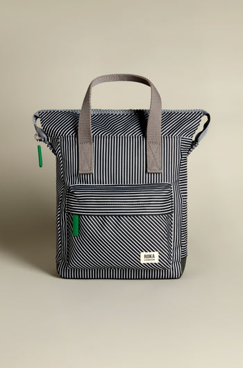 The Recycled Canvas Stripe Bantry Bag is a black and white striped backpack with gray handles and a front zipper pocket.