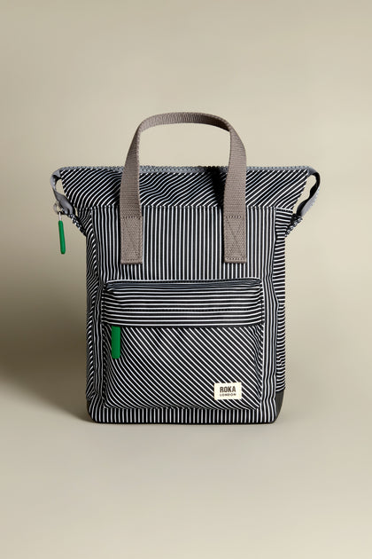 The Recycled Canvas Stripe Bantry Bag is a black and white striped backpack with gray handles and a front zipper pocket.