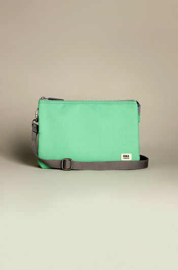 The Recycled Canvas Carnaby Crossbody Bag features a rectangular mint green pouch with a gray adjustable strap and zipper, all made from recycled canvas against a neutral backdrop.