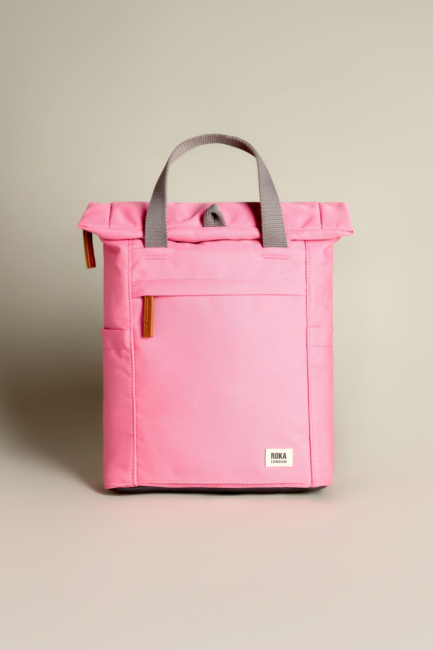 The Recycled Canvas Small Finchley Bag, featuring pink with gray handles and a front pocket, is made from eco-friendly materials and showcased against a neutral background.