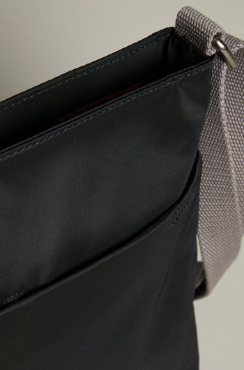 Close-up of the Recycled Nylon Kennington Crossbody Bag in sleek black, featuring a gray strap and an exterior pocket.