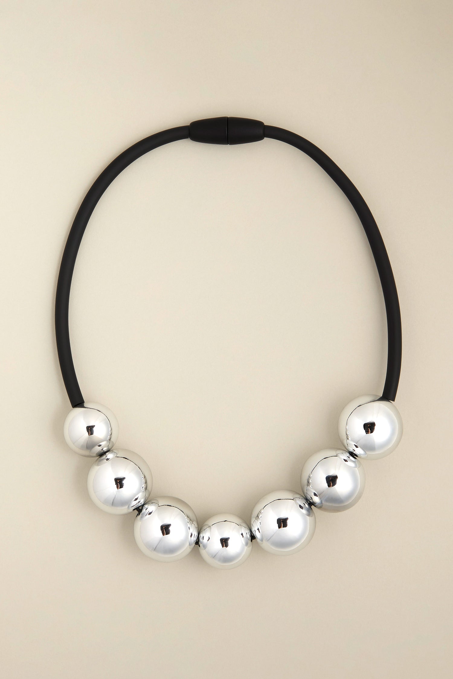 Presenting the 7 Spheres Necklace by Samuel Coraux: a striking creation featuring seven large silver spheres set against black bands, radiating contemporary elegance on a subtle background.