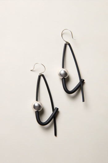 Silver Sphere Earrings: Abstract black drop earrings featuring curved lines and silver sphere accents, displayed on a light neutral background—an eye-catching example of modern jewellery design.