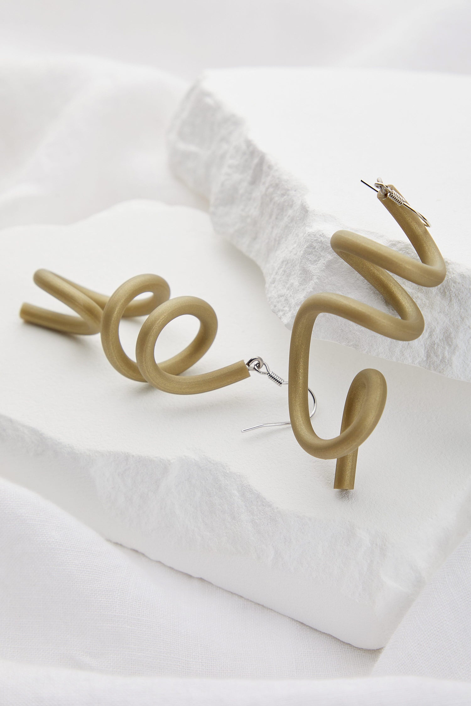 Sketch Earrings resting on a white textured surface, a contemporary piece by Samuel Coraux.