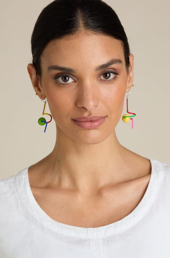 A woman wearing a white top and the vibrant Sketch Ball Earrings is looking directly at the camera against a plain background.