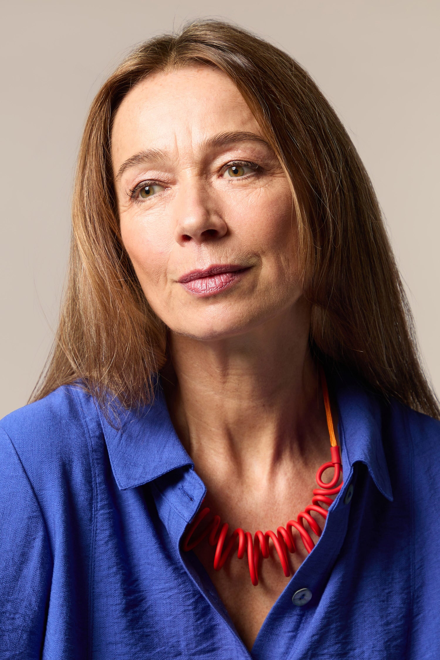 A woman wearing a blue shirt and the Citrus Squiggle Necklace with a strong visual identity.