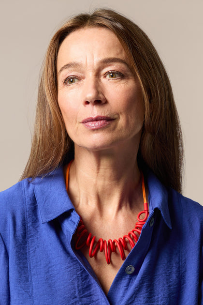 A woman in a blue shirt with a contrasting Citrus Squiggle Necklace.