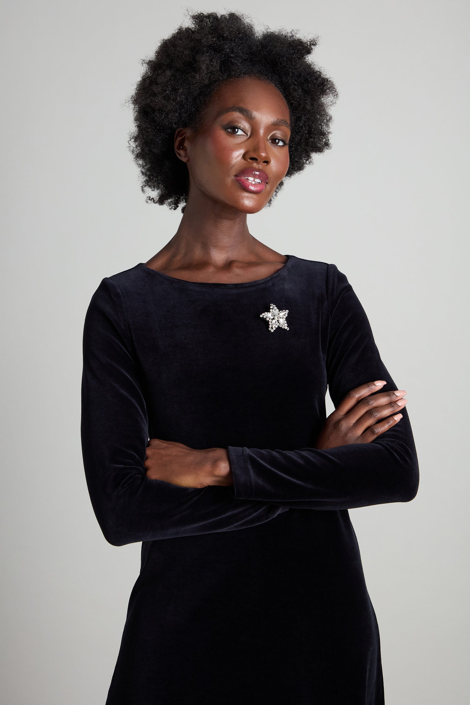 A person in a black velvet dress adorned with the Star Brooch, encrusted with rhinestones, stands against a plain background.