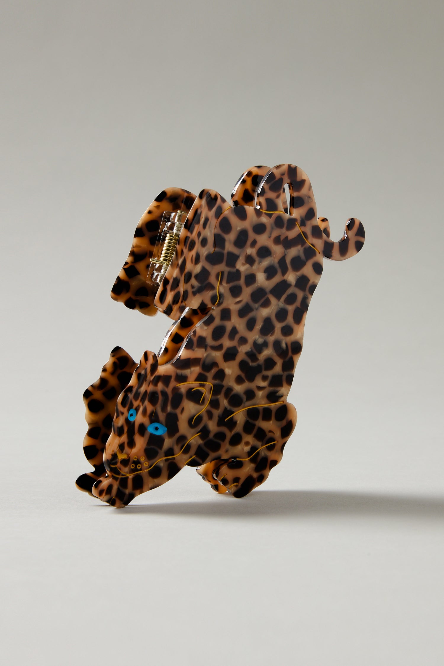 The Hand Painted Leopard Hair Clip is an eco-friendly accessory made from biodegradable acetate, designed in the shape of a standing leopard with a stylish leopard-print pattern.