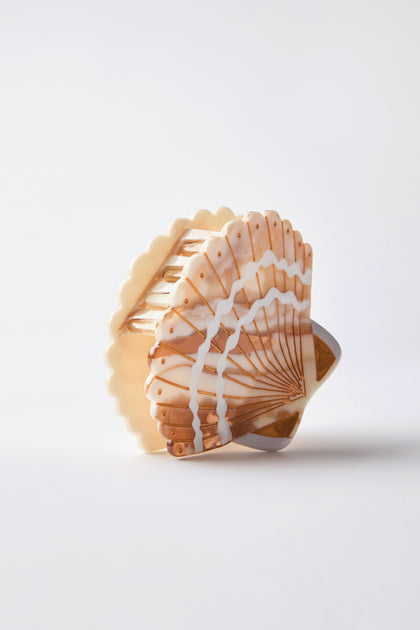 The Hand Painted Seashell Hair Clip is a large, multicolored hair claw with an abstract shell design, capturing seaside charm on a plain background.