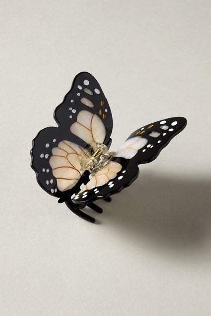 The Hand Painted Monarch Butterfly hair clip, made from biodegradable acetate with a silver clasp, showcases a black and white design on a light gray surface, embodying eco-friendly artistry while adding charm to any hairstyle.