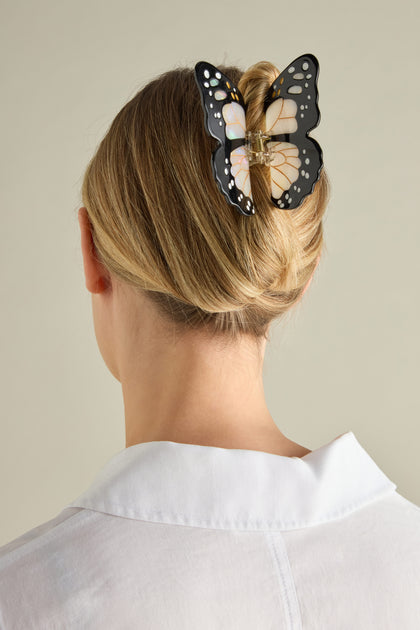 A person with light-colored hair wears an exquisite Hand Painted Monarch Butterfly Hair Clip, showcasing eco-friendly artistry.