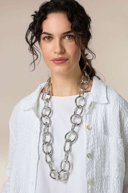 A woman wearing a classic white shirt and the Long Silver Links Necklace with a fresh sheen.