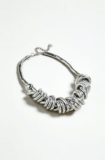 The Woven Silver Necklace features chunky interlocking rings in a clustered design, showcased against a plain white background.