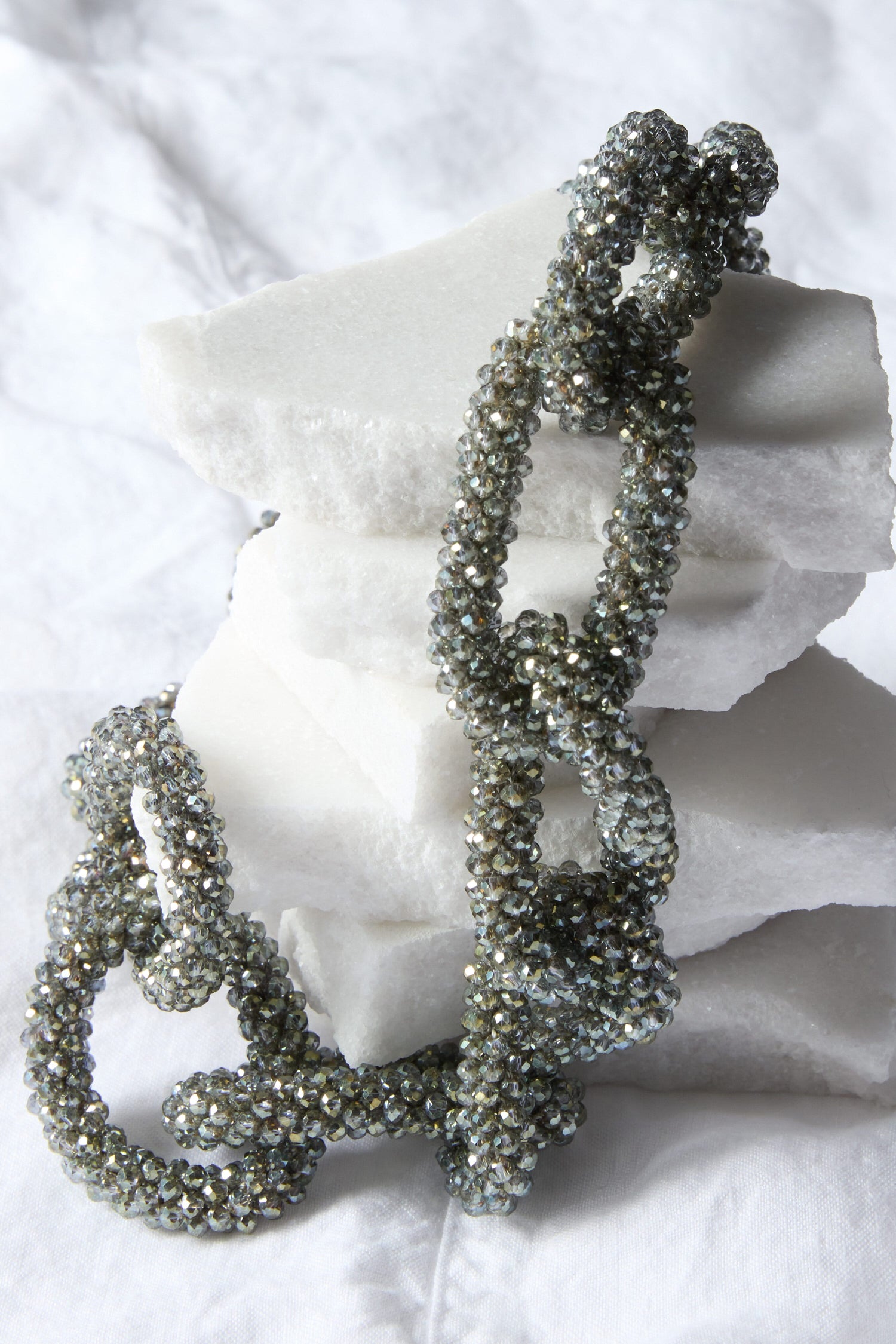 A Glacier Necklace is laying on top of a pile of white stones.