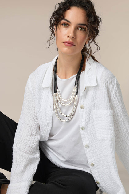 A woman wearing a white shirt and black pants accessorized with a Layered Silver Spheres Necklace.