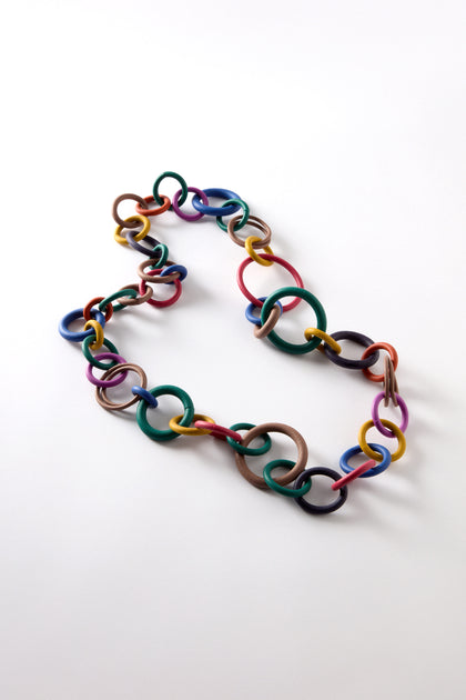 The Long Rainbow Hoops Necklace features a vibrant tumble of playful, interlinked multicolored rings, elegantly arranged on a plain white background.