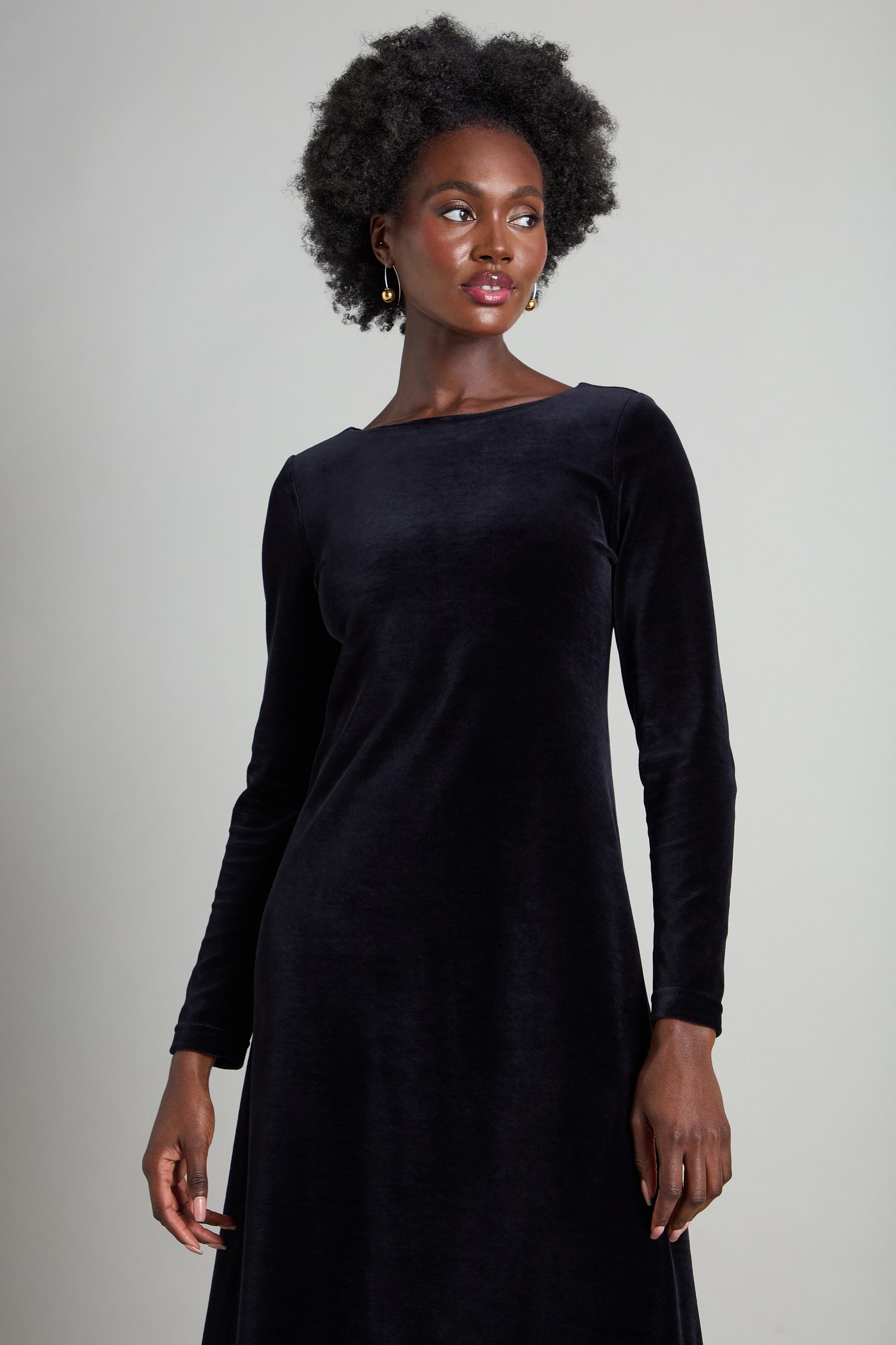 A person graces a neutral background in a Velvet Jersey Maxi A-Line Dress that captures understated glamour with its fit-and-flare silhouette.