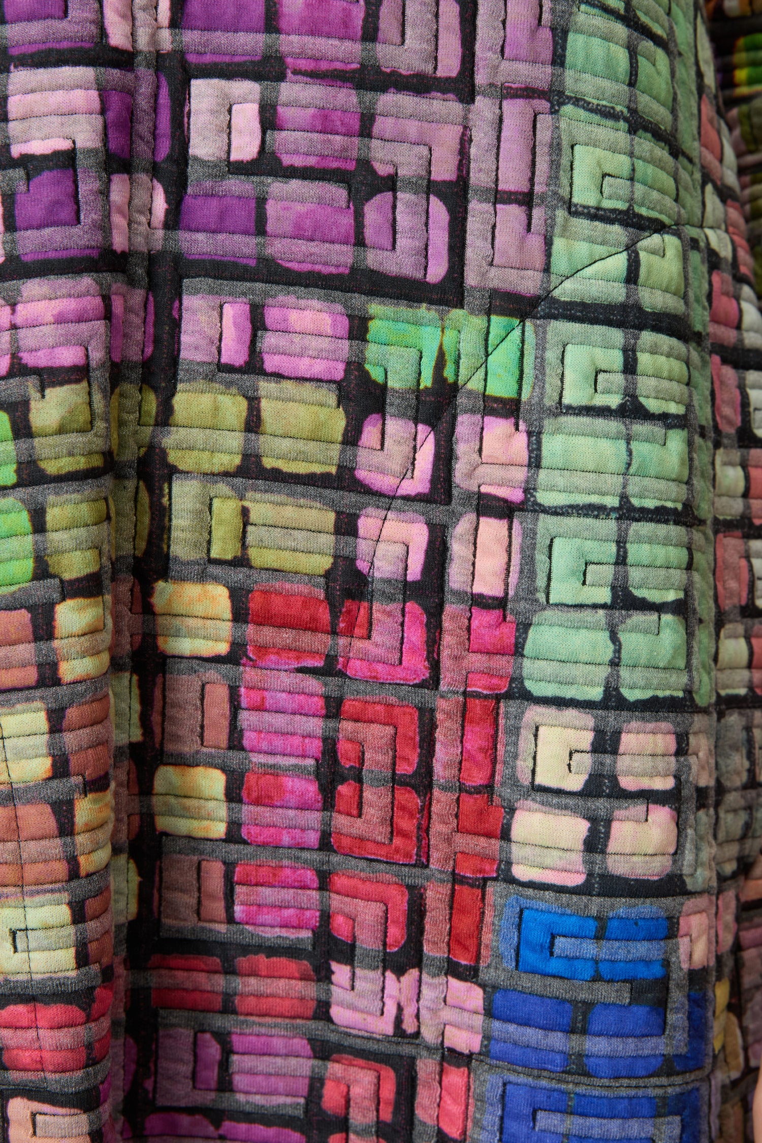 Close-up of the Coloured Glass Tiles Jersey Bubble Dress, showcasing a geometric pattern of pink, green, blue, and purple squares and rectangles outlined in black, reminiscent of coloured glass tiles.