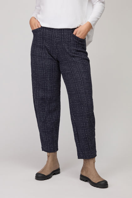 Model wears Boucle Cotton Jersey Bubble Trouser in navy blue with a white long-sleeve top and tan ankle boots. Hands in pockets; only the lower half of the body is shown.