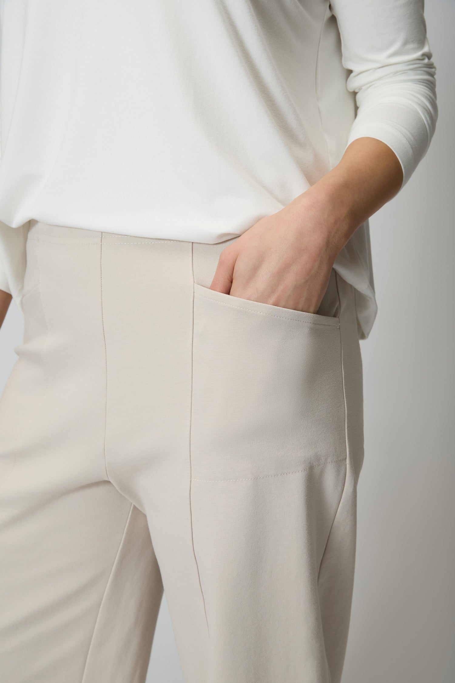 A person wearing Ecru Ponte Bubble Trouser with a bubble leg silhouette and a white long-sleeve top has their right hand in their pocket.