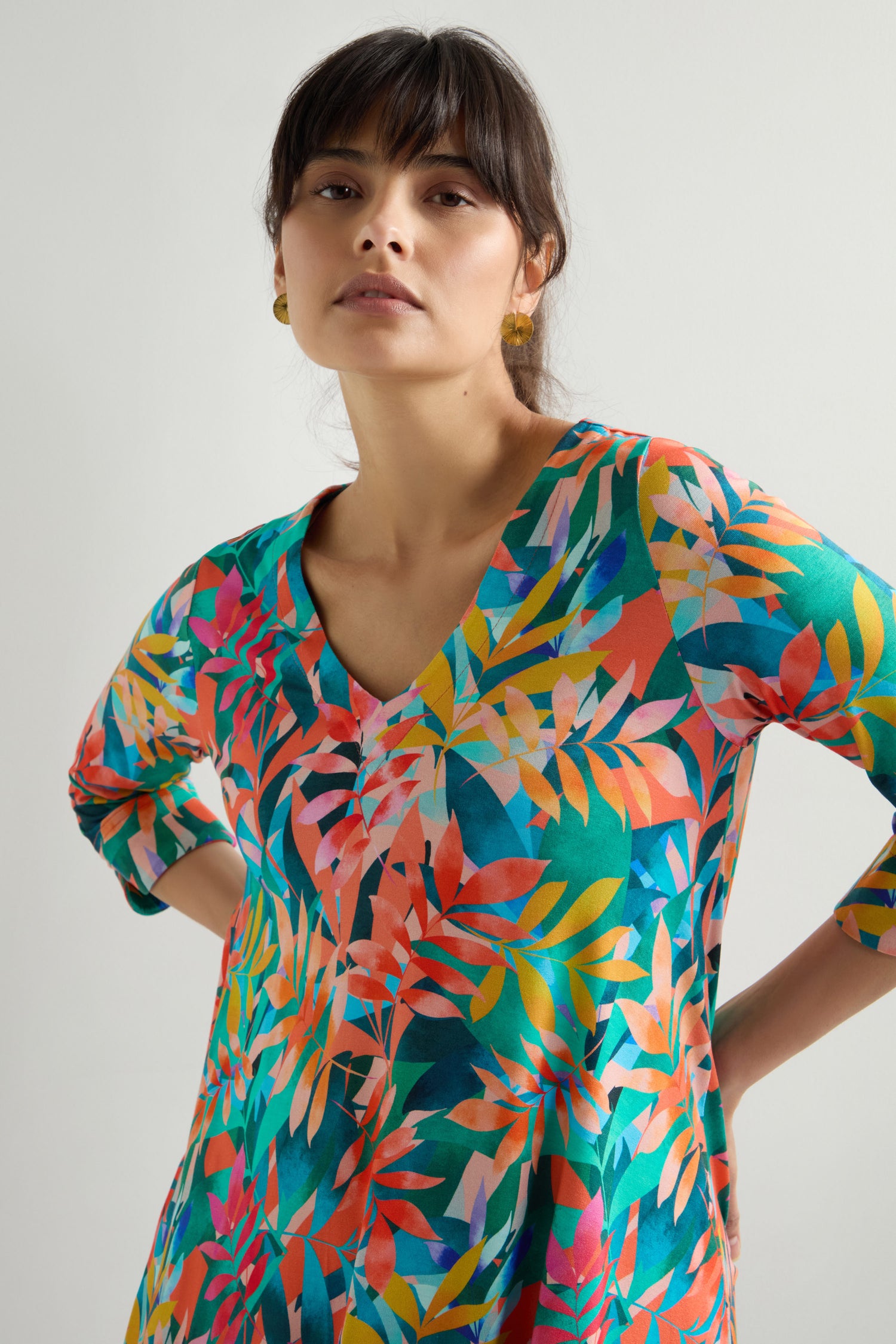 A person is wearing a Tropical Leaves Jersey Print Tunic with a V-neck, showcasing a flattering fit against a plain background.