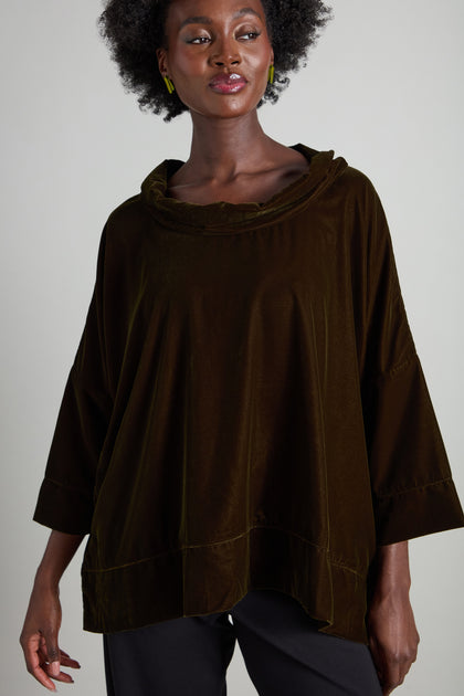 A person wears the Cowl Neck Boxy Top in dark brown velvet, featuring shell button-up detailing and 3/4 length flared sleeves, paired with black pants.