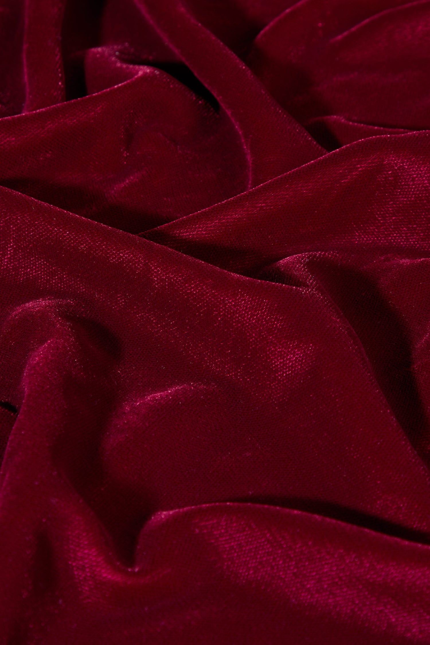 Close-up of crumpled deep red velvet fabric with a soft texture, reminiscent of a luxurious top.