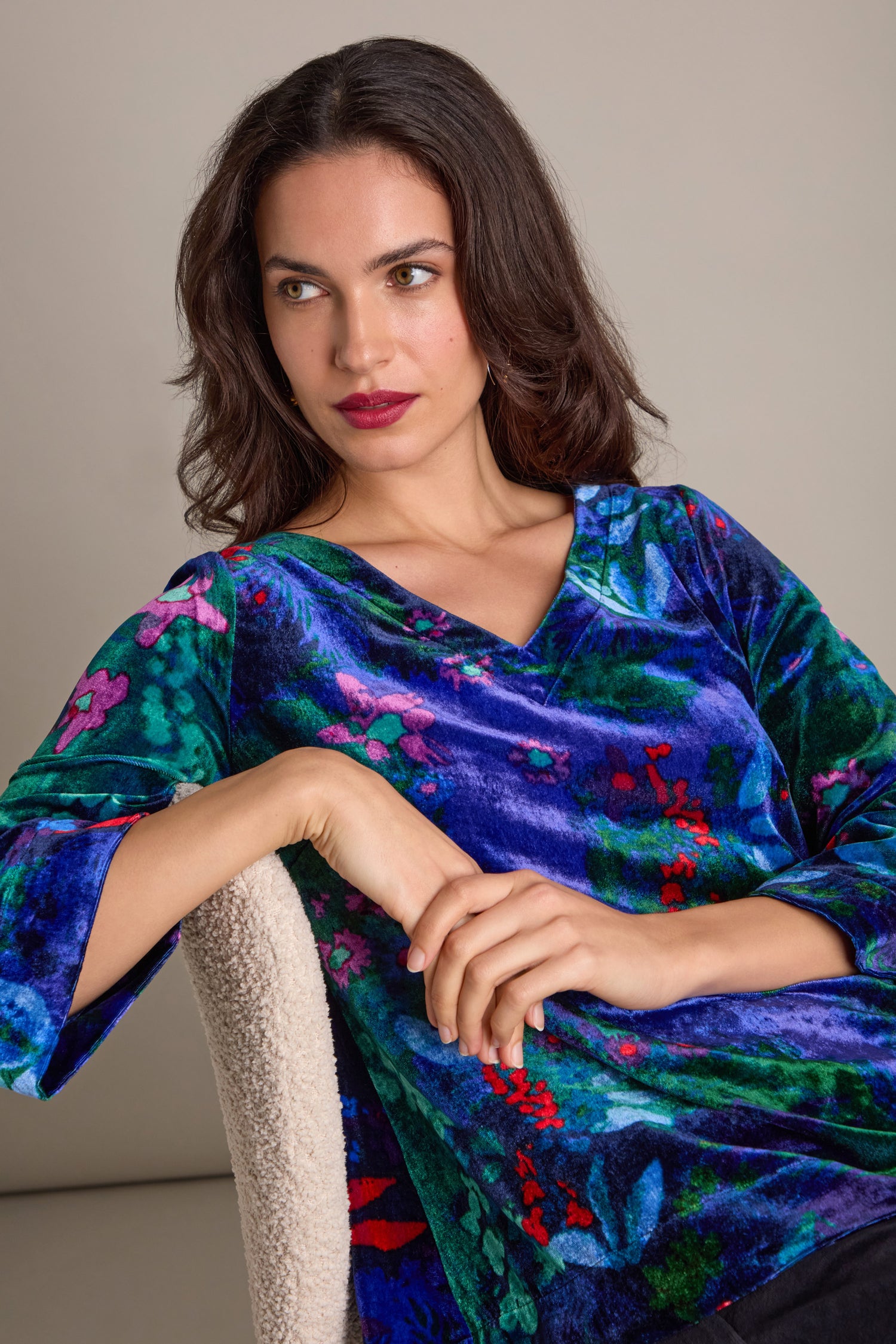 A person wearing the Late Night Flora Velvet Top, seated with hands clasped, looking sideways.