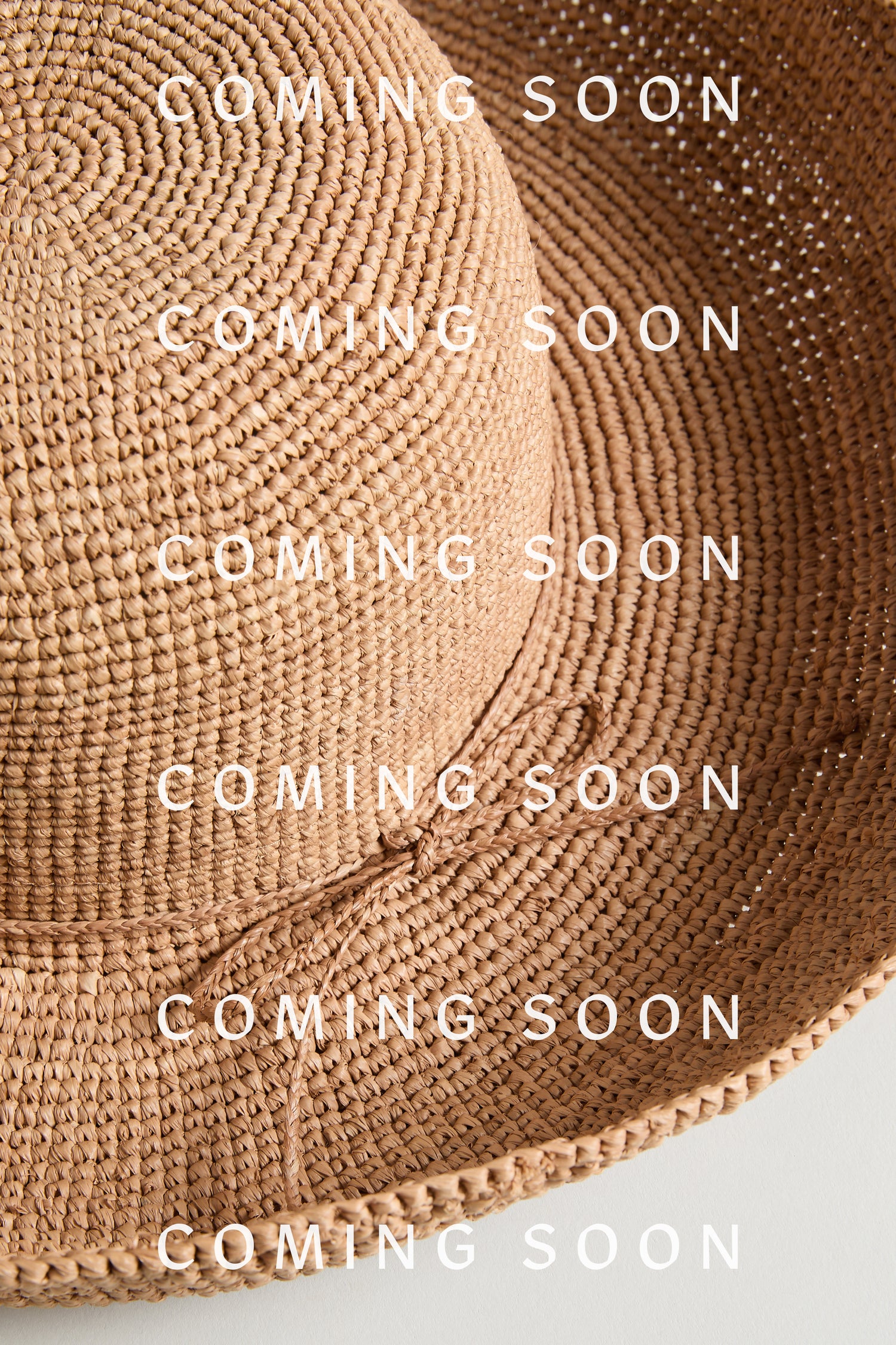 A Handwoven Raffia Tie Hat with “COMING SOON” text repeatedly overlaid across the image.