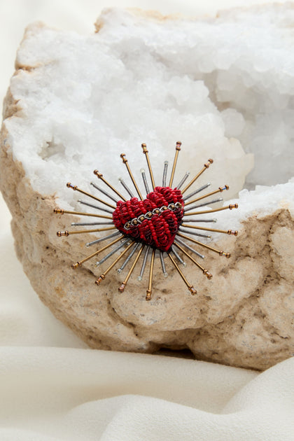 A Sacred Heart Embroidered Brooch on top of a rock.