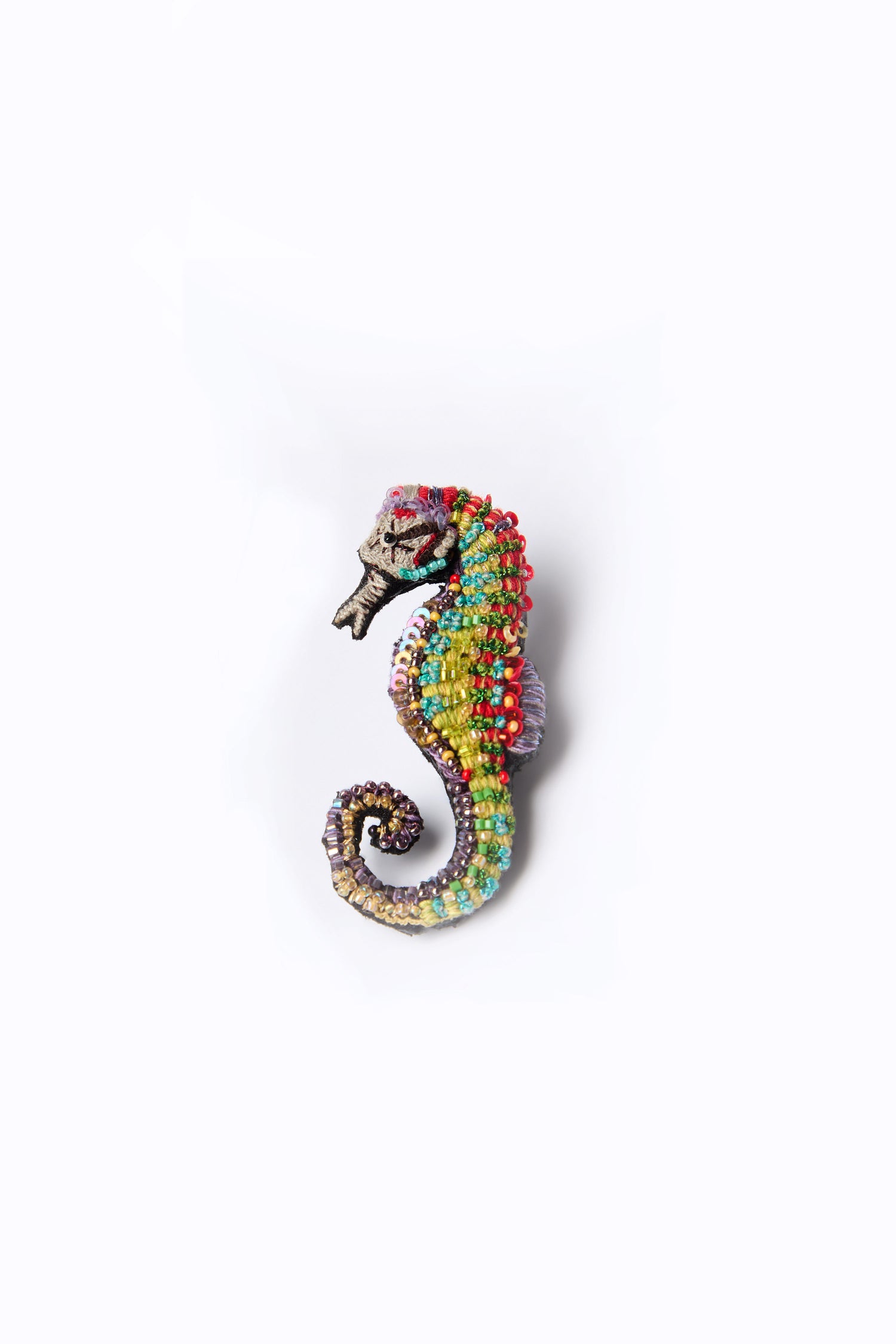 The Hand Beaded Spotted Seahorse Brooch by Trovelore features a vibrant seahorse design on a pristine white background, intricately adorned with hand-beaded embellishments.