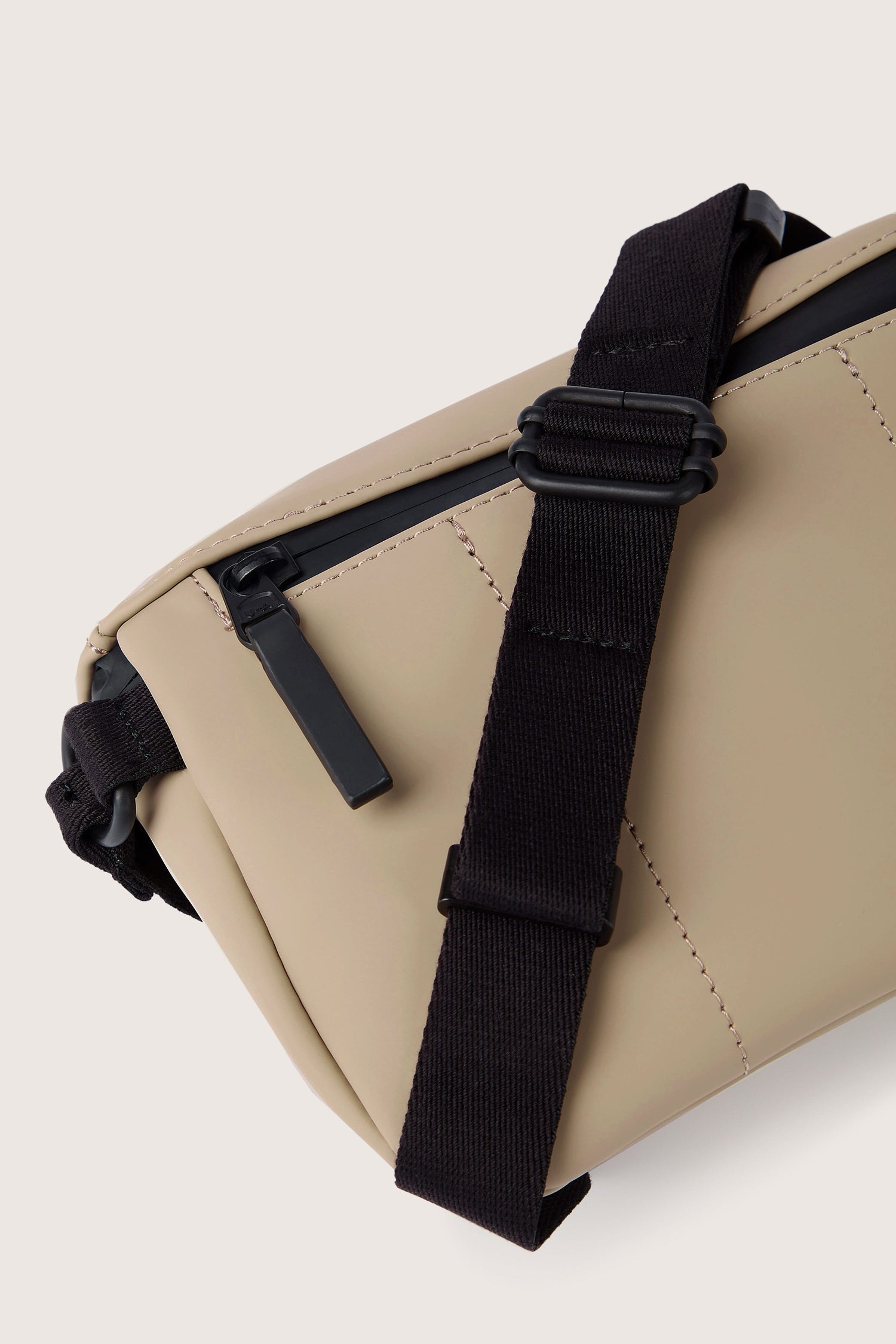 Close-up of the Jona Crossbody Bag with black zipper and strap, highlighting the stitching details and the strap's buckle mechanism, crafted from durable, water-repellent vegan tech material.