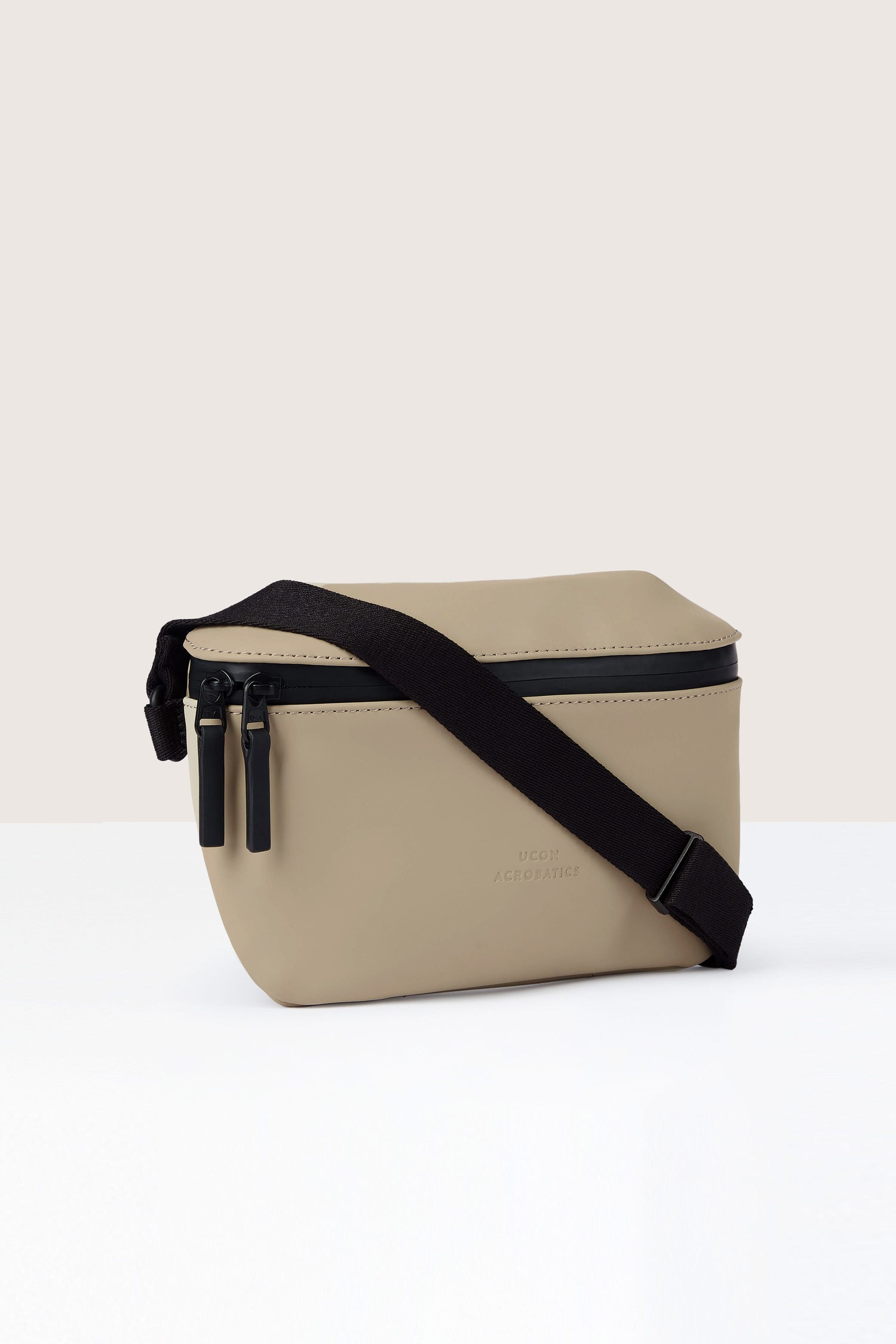 A Jona Crossbody Bag crafted from water-repellent vegan tech material, featuring a black adjustable strap and dual zipper closures, set against a plain background.