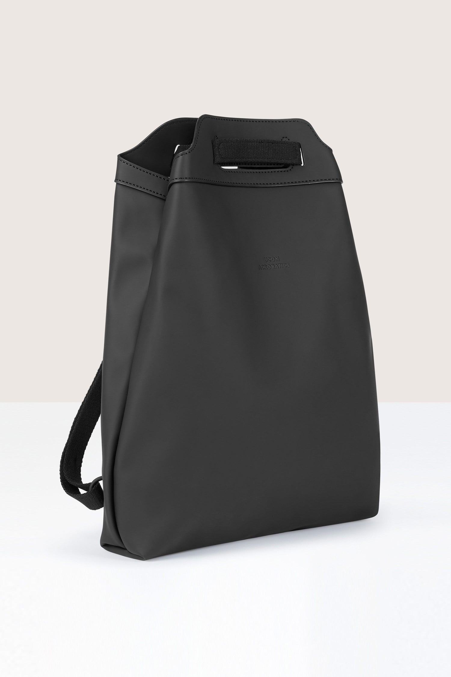 The Una Backpack is a sleek, black, rectangular backpack with a minimalist design, featuring a top handle and shoulder straps. Crafted from recycled PET bottles, it boasts a versatile design perfect for any occasion.