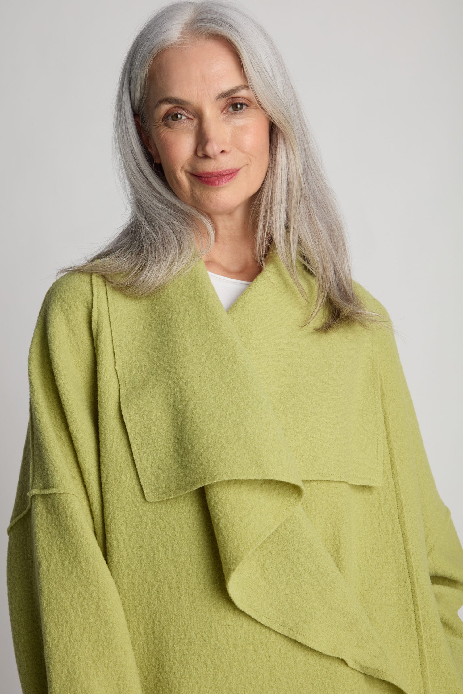 A person with long gray hair, dressed in a light green Shawl Collar Boiled Wool Coat, stands against a plain background, looking at the camera.