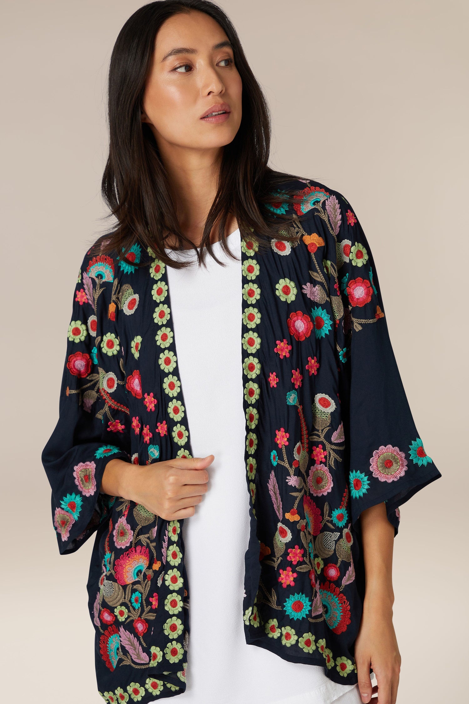 A woman wearing a white top and the Embroidered Flower Garden Kimono.