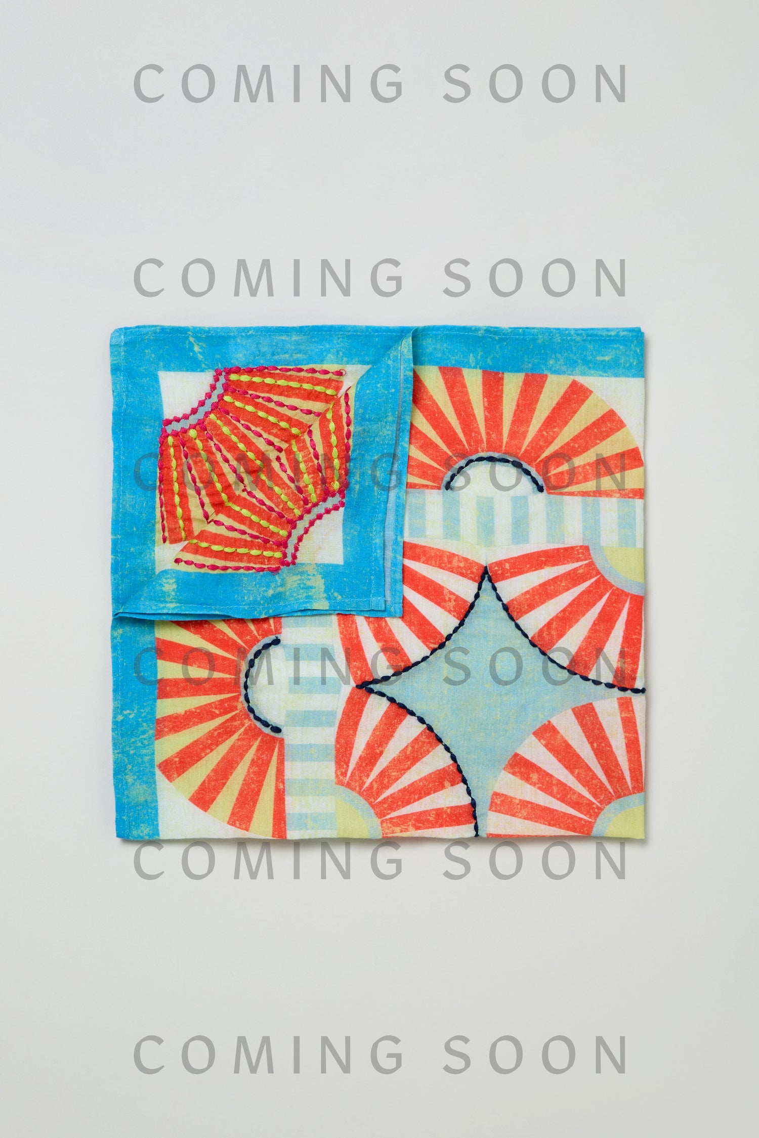 The Embroidered Parasols Cotton Bandana displays geometric fan motifs in red, blue, and white with black stitching. The phrase "COMING SOON" is repeatedly overlaid on the image.