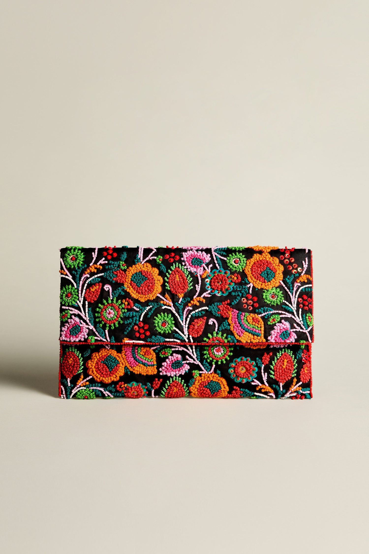 The Wild Garden Hand Beaded Clutch Bag showcases vibrant floral and bird embroidery against a dark background, making it a stunning statement accessory.